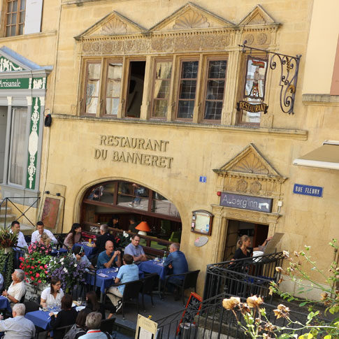 La pierre jaune de Neuchâtel fait briller les façades des bâtiments, comme ici le restaurant du Banneret