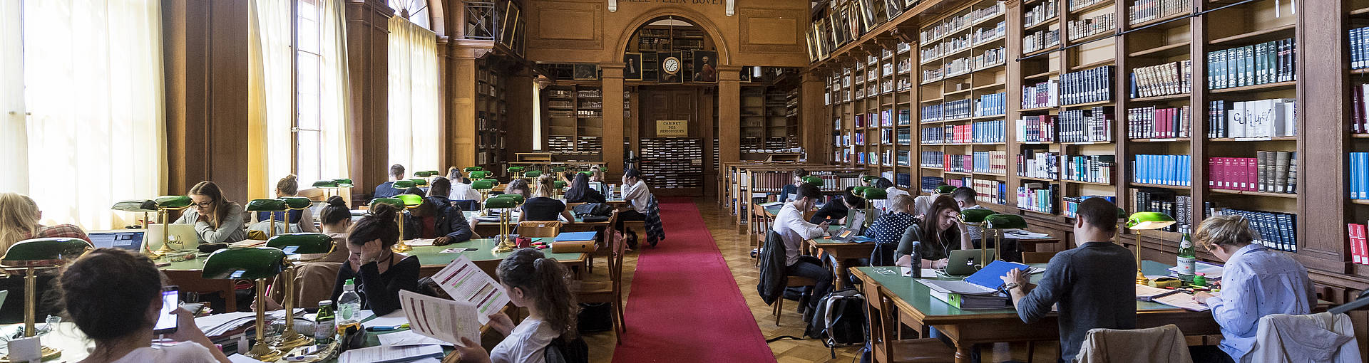 L'intérieur de la bibliothèque publique de Neuchâtel, avec des rayonnages de livres et des étudiants attentifs