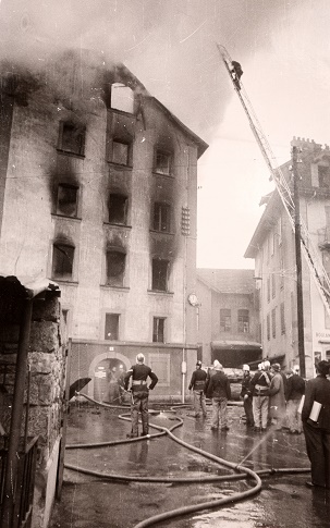 Immeuble incendié avec pompier sur une échelle.