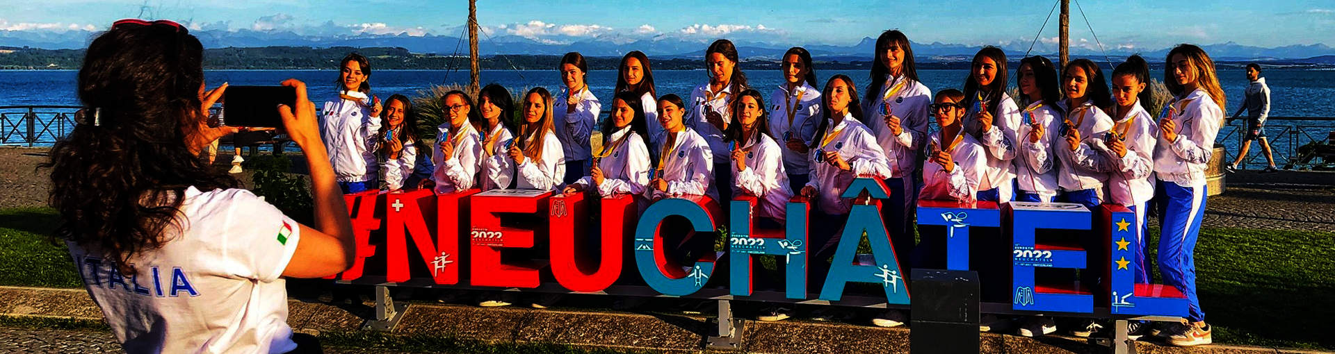 Des gymnastes posent derrière le hashtag Neuchâtel sur l'esplanade du Mont-blanc